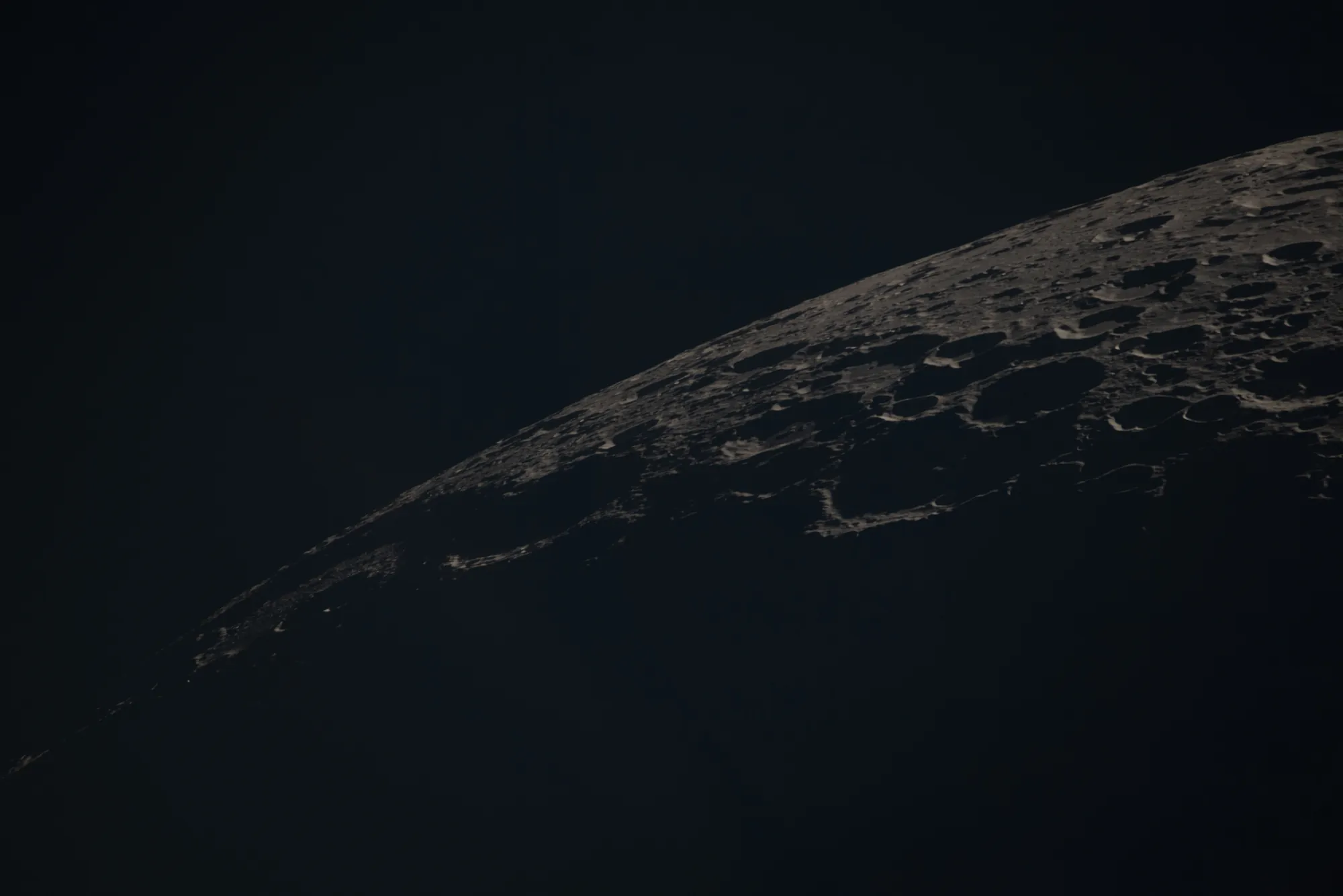 Borda curva da Lua com crateras iluminadas em ângulo baixo e sombras longas